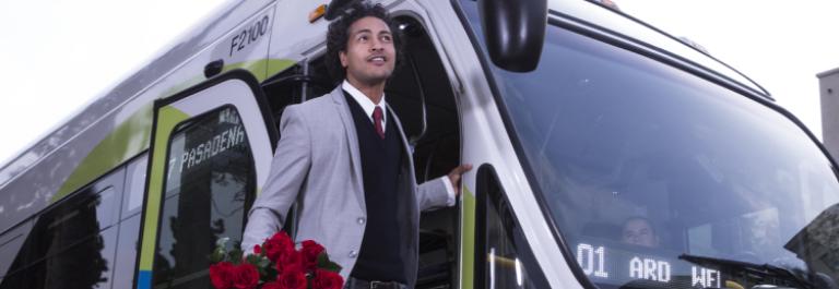 Smiling customer gets off bus holding roses.